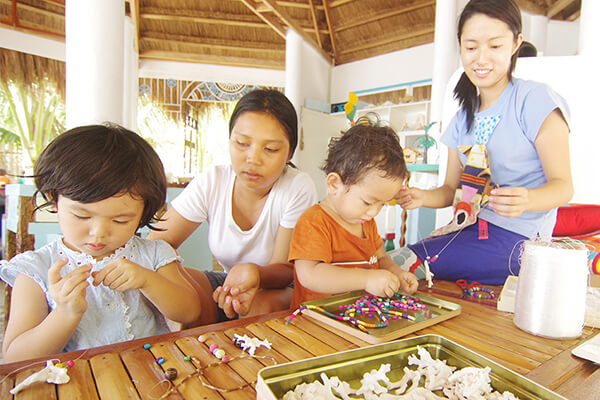 フィリピン人女性とアクセサリー作りをする日本人の子どもたち